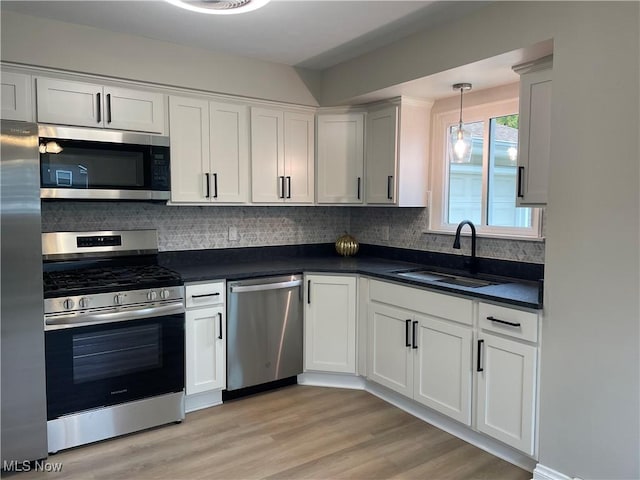 kitchen with sink, light hardwood / wood-style flooring, white cabinets, stainless steel appliances, and backsplash