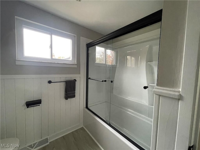 bathroom with wood-type flooring and shower / bath combination with glass door