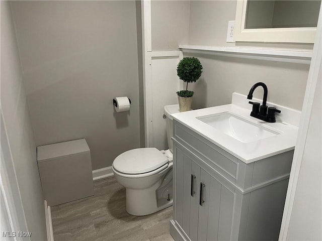 bathroom featuring wood-type flooring, vanity, and toilet