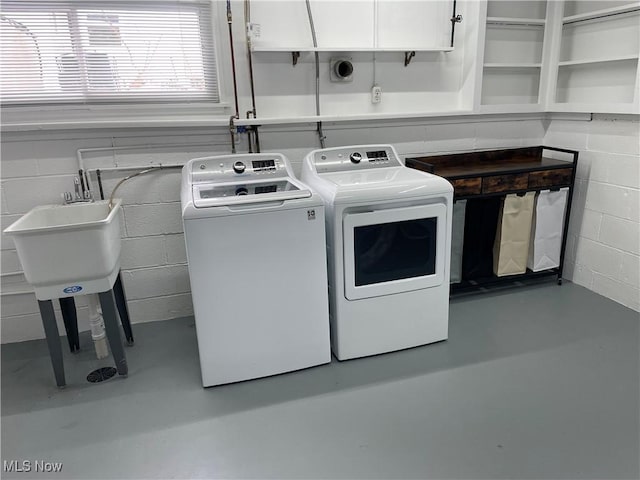 clothes washing area featuring washing machine and dryer and cabinets