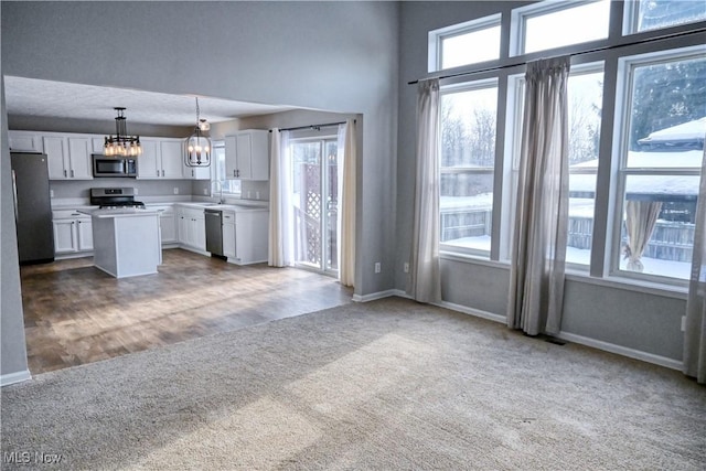 kitchen featuring pendant lighting, sink, stainless steel appliances, a center island, and white cabinets