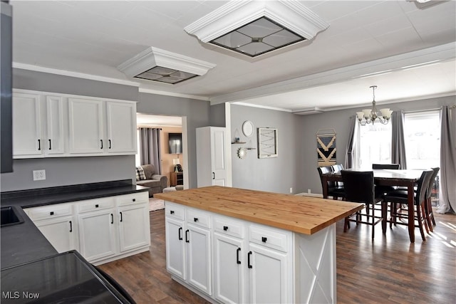 kitchen with crown molding, dark wood-type flooring, butcher block counters, white cabinets, and decorative light fixtures