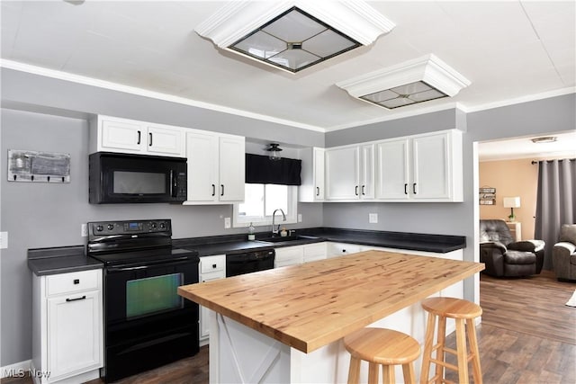 kitchen featuring a kitchen island, sink, a breakfast bar area, white cabinets, and black appliances