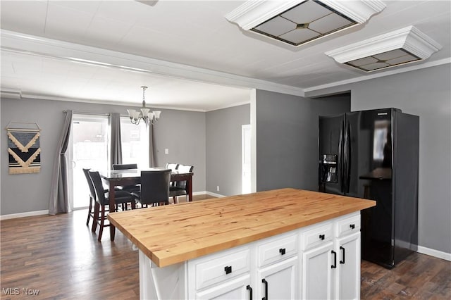 kitchen featuring butcher block counters, black fridge with ice dispenser, white cabinetry, decorative light fixtures, and a center island