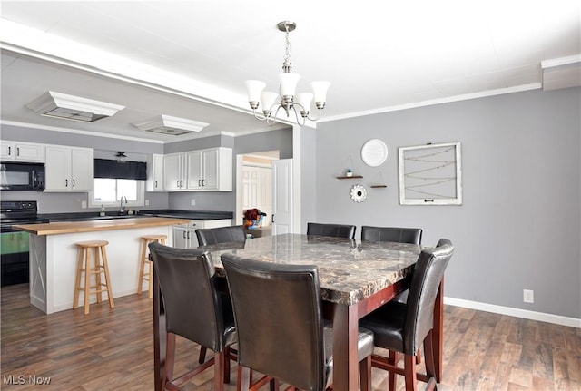 dining room featuring ornamental molding, dark wood-type flooring, sink, and a notable chandelier