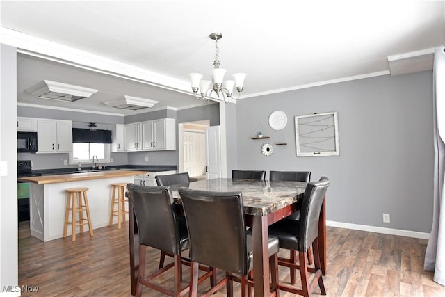 dining room featuring ornamental molding, dark hardwood / wood-style floors, a chandelier, and sink