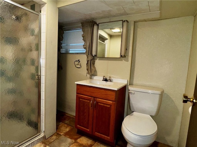 bathroom featuring a shower with door, vanity, and toilet