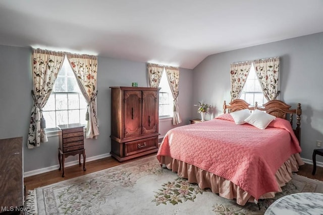 bedroom with multiple windows, vaulted ceiling, and hardwood / wood-style flooring