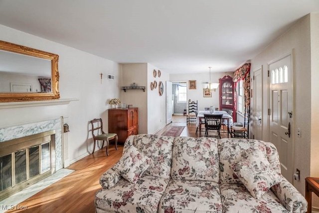 living room with a high end fireplace and light hardwood / wood-style flooring