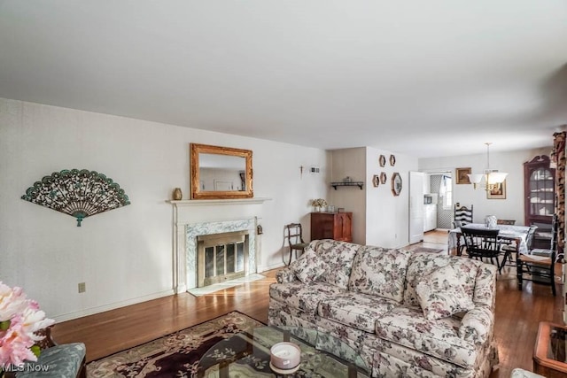 living room featuring hardwood / wood-style flooring, a premium fireplace, and a chandelier