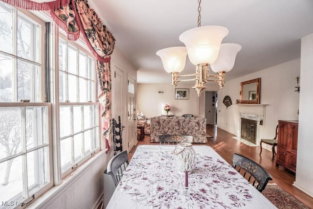 dining space featuring dark wood-type flooring, a high end fireplace, and an inviting chandelier