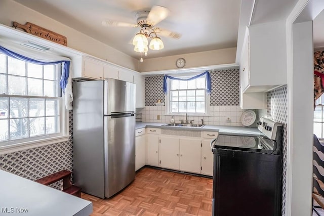 kitchen with sink, stainless steel refrigerator, light parquet floors, white cabinets, and decorative backsplash