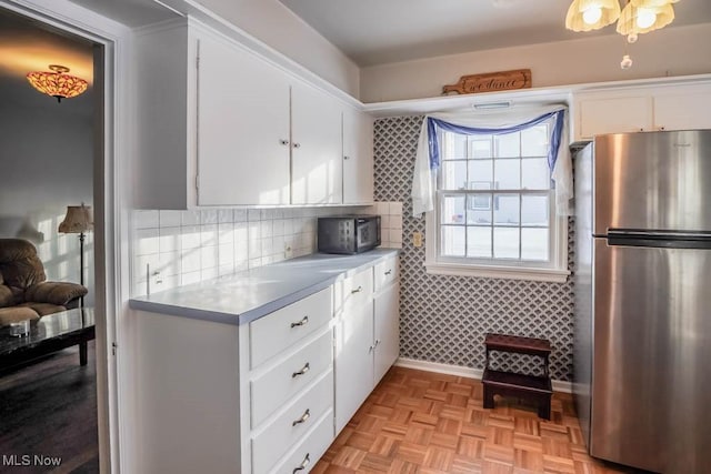 kitchen featuring white cabinetry, light parquet flooring, and stainless steel refrigerator