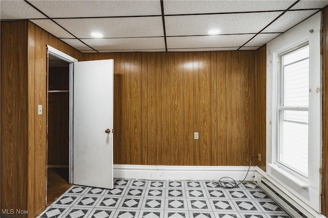 empty room featuring a drop ceiling and wood walls