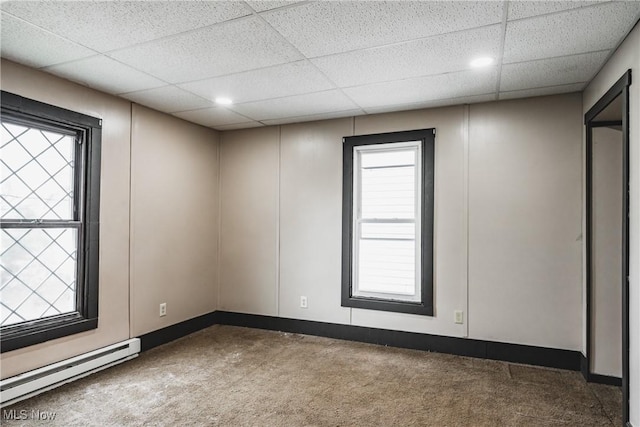 spare room with a baseboard radiator, carpet floors, and a drop ceiling