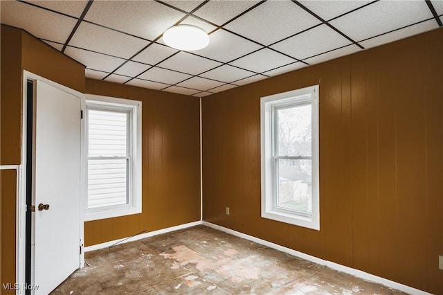 spare room featuring a paneled ceiling and wood walls