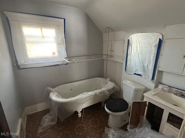 bathroom featuring vanity, lofted ceiling, a bathtub, and toilet