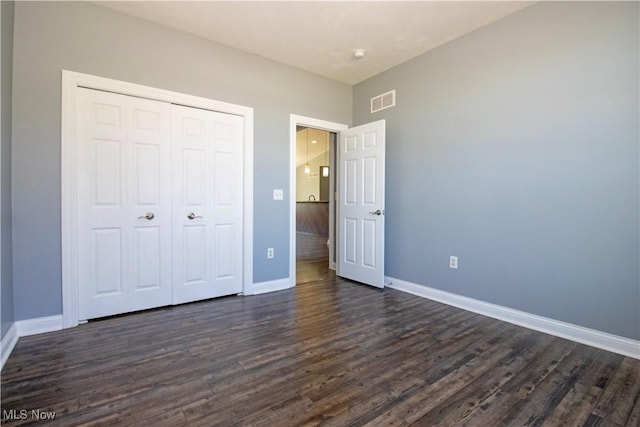 unfurnished bedroom featuring dark hardwood / wood-style flooring and a closet