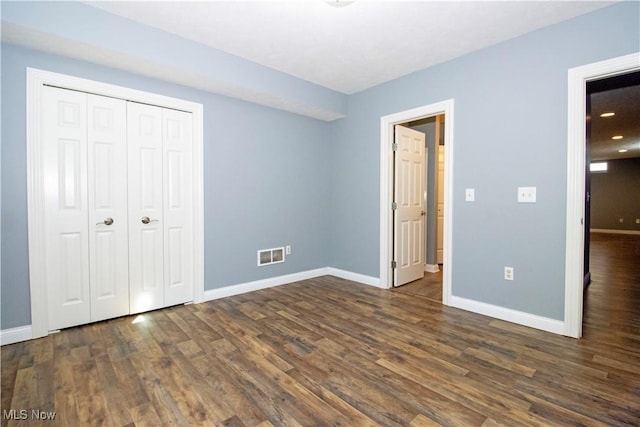 unfurnished bedroom featuring dark wood-type flooring and a closet