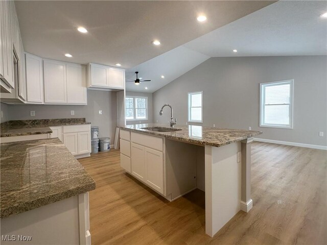 kitchen featuring sink, a kitchen island with sink, light hardwood / wood-style flooring, and white cabinets