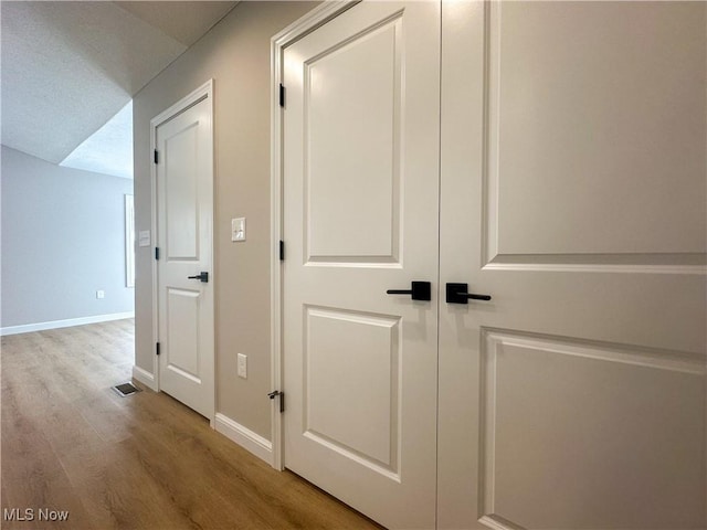 corridor featuring light hardwood / wood-style floors and a textured ceiling