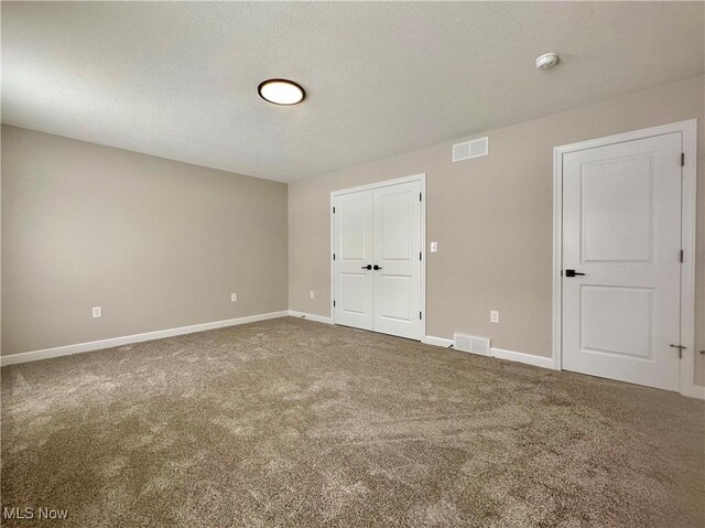 spare room featuring carpet flooring and a textured ceiling