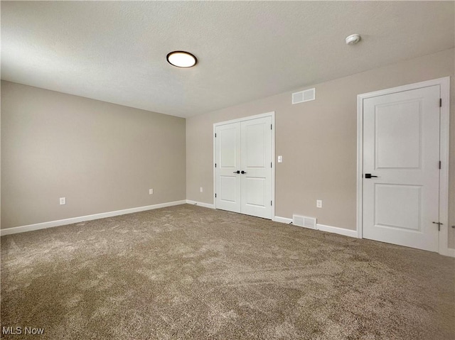 carpeted empty room with a textured ceiling, visible vents, and baseboards