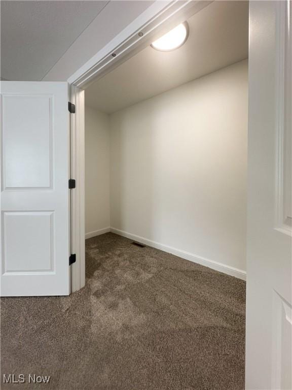 empty room featuring carpet and baseboards