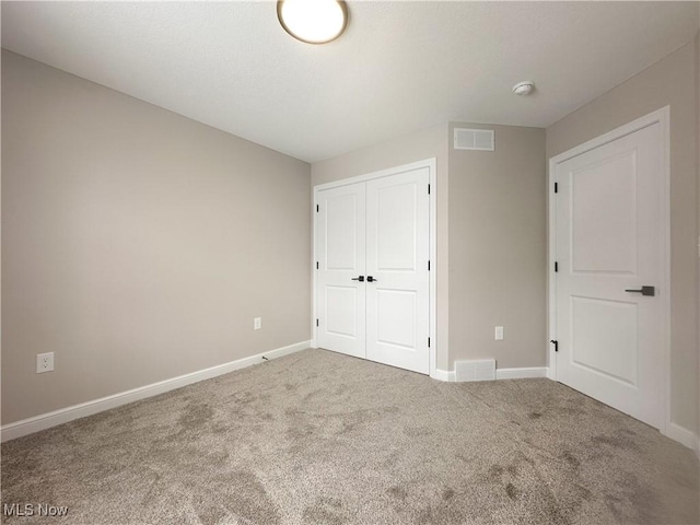 unfurnished bedroom with carpet floors, a closet, visible vents, and baseboards