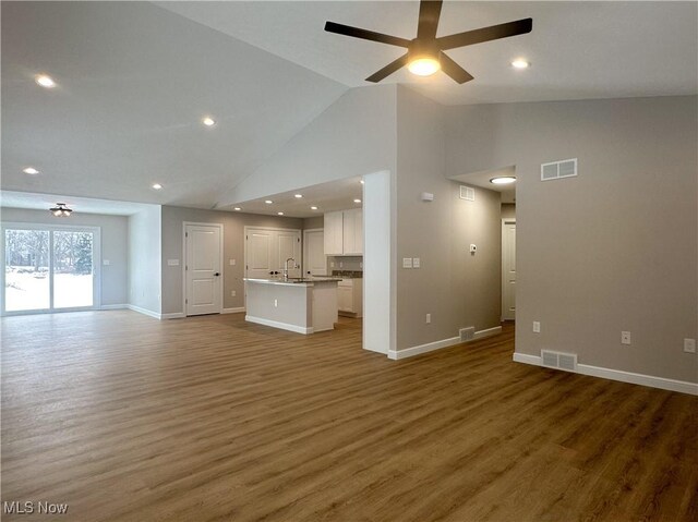 unfurnished living room featuring ceiling fan, dark wood-type flooring, sink, and high vaulted ceiling