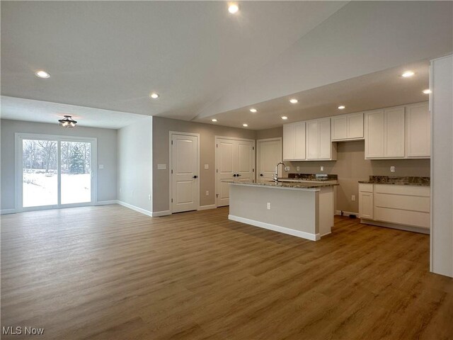 kitchen featuring hardwood / wood-style floors, white cabinetry, sink, and a center island with sink