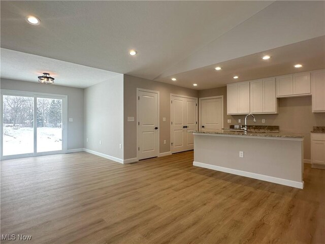 kitchen featuring white cabinetry, light hardwood / wood-style floors, and a center island with sink