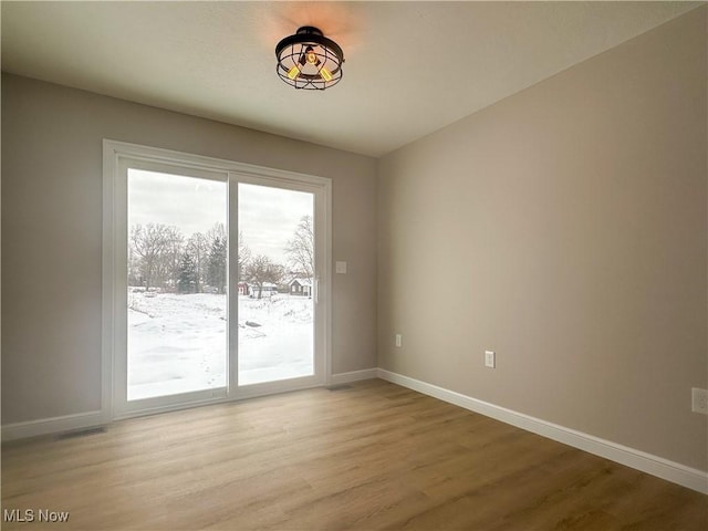 spare room featuring light wood finished floors and baseboards