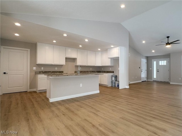 kitchen with open floor plan, light wood-style floors, lofted ceiling, and white cabinets