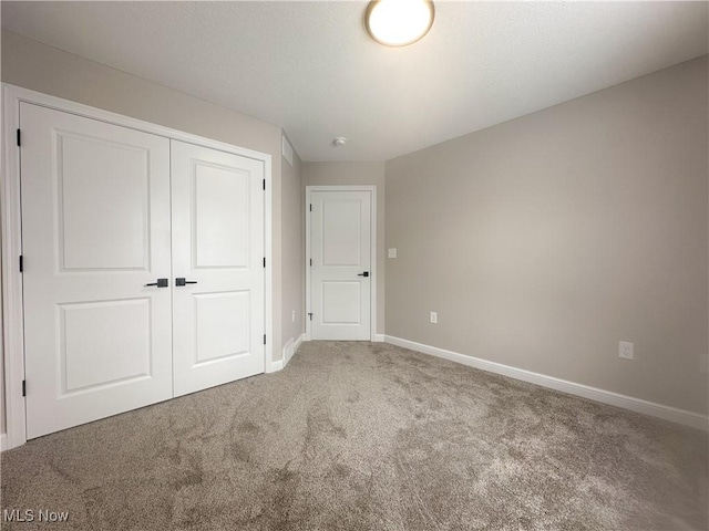 unfurnished bedroom with carpet floors, a closet, and baseboards