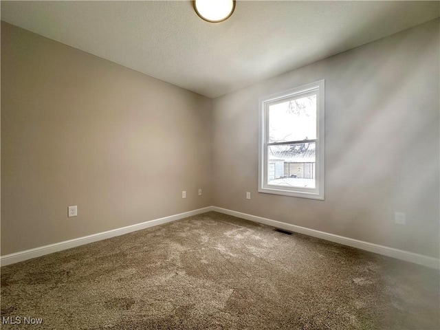 empty room with baseboards, visible vents, and carpet flooring