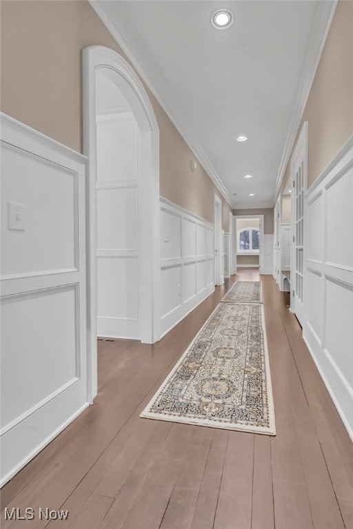 corridor with ornamental molding and hardwood / wood-style floors