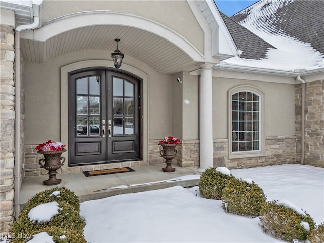 snow covered property entrance featuring french doors