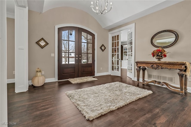 entryway featuring lofted ceiling, dark hardwood / wood-style flooring, french doors, and an inviting chandelier