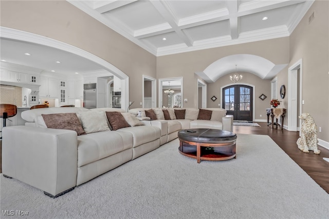 living room with beam ceiling, dark hardwood / wood-style floors, coffered ceiling, french doors, and a chandelier