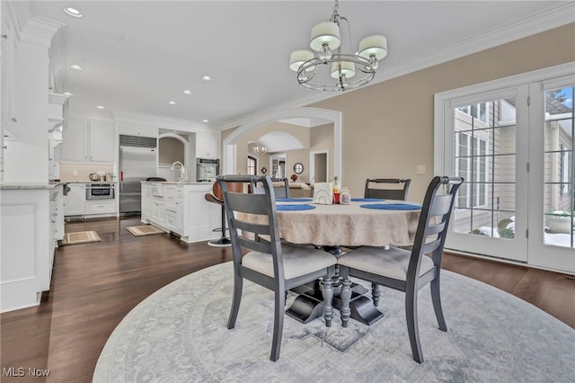 dining room featuring crown molding, dark wood-type flooring, and an inviting chandelier