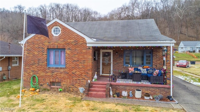 bungalow-style home featuring covered porch and a front lawn