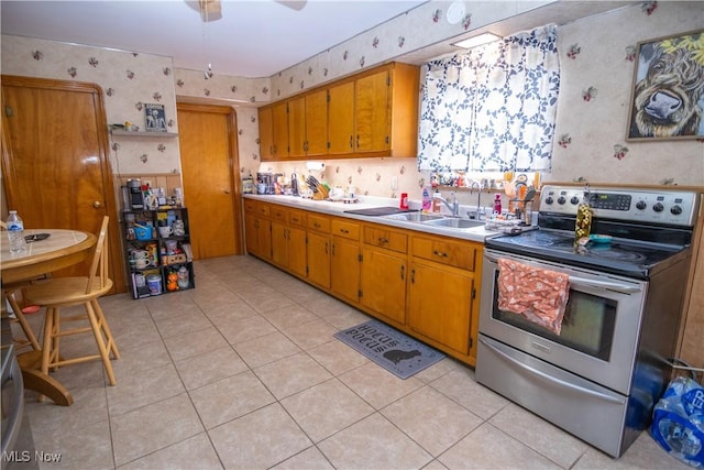 kitchen featuring sink, light tile patterned floors, ceiling fan, and stainless steel electric range