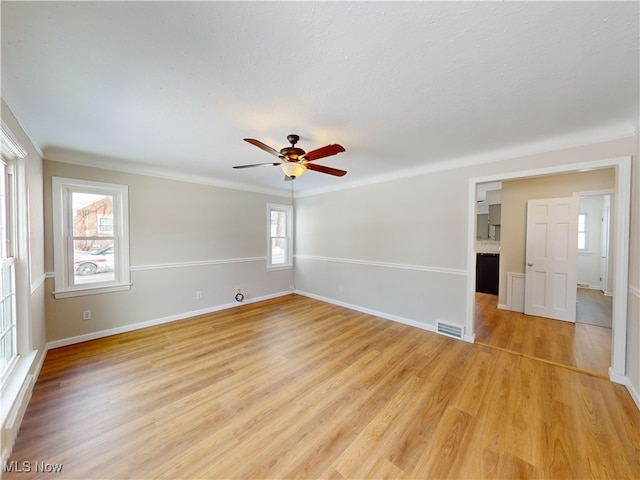 empty room featuring light hardwood / wood-style flooring, ornamental molding, and ceiling fan