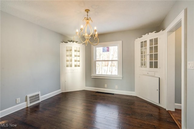 unfurnished dining area featuring dark hardwood / wood-style flooring and an inviting chandelier