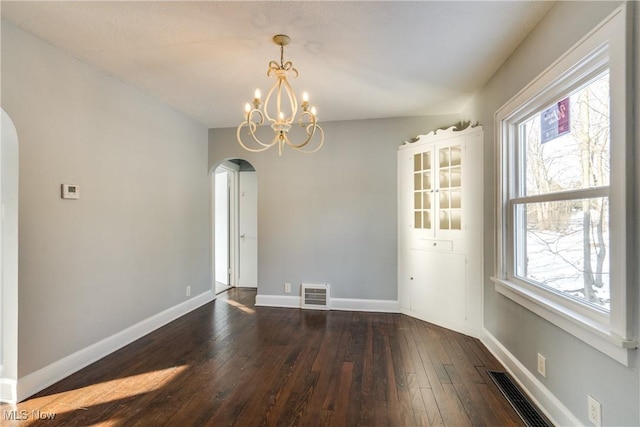 unfurnished room with dark wood-type flooring and a notable chandelier