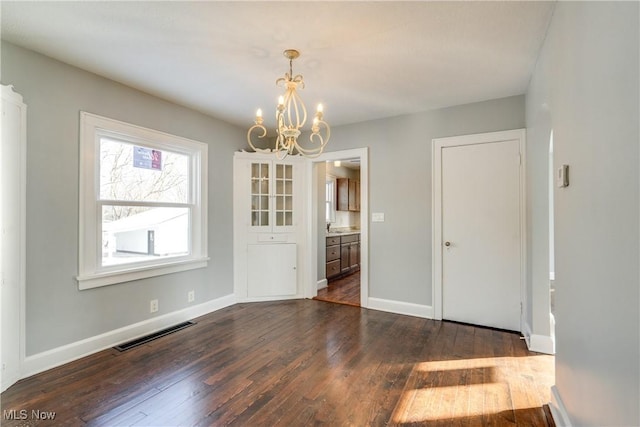 unfurnished dining area featuring dark hardwood / wood-style floors and a chandelier