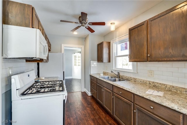 kitchen featuring sink, ceiling fan, light stone counters, dark wood-type flooring, and white appliances