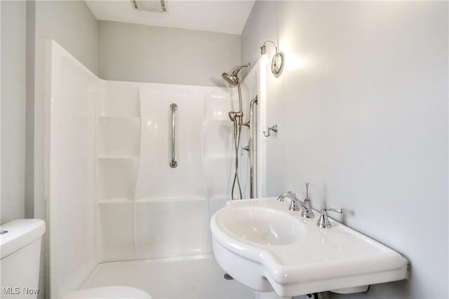 bathroom featuring walk in shower, sink, and toilet