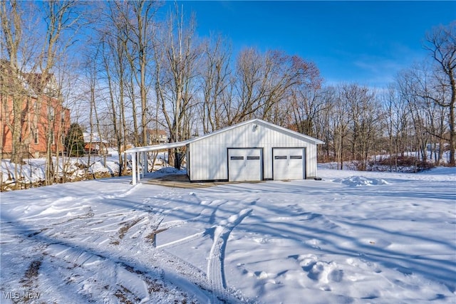 snow covered structure featuring a garage and a carport